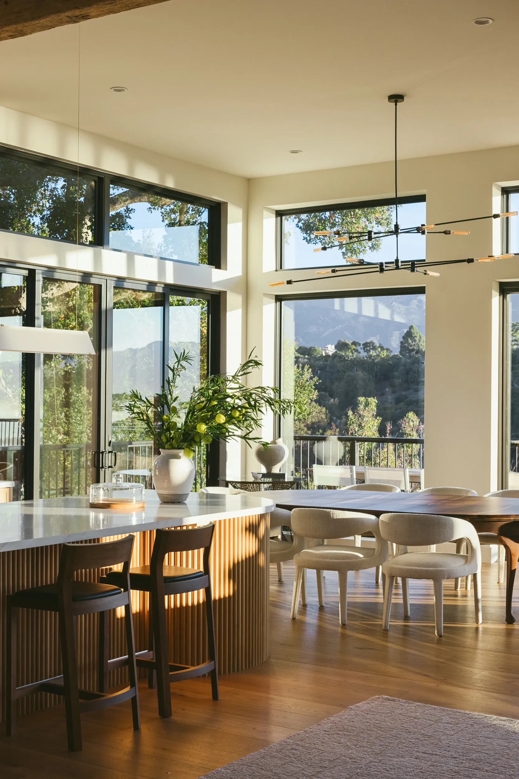 Modern kitchen with fluted wood island, marble countertops, and dining area overlooking mountain views through floor-to-ceiling windows House Rupert interior design Santa Barbara and Montecito